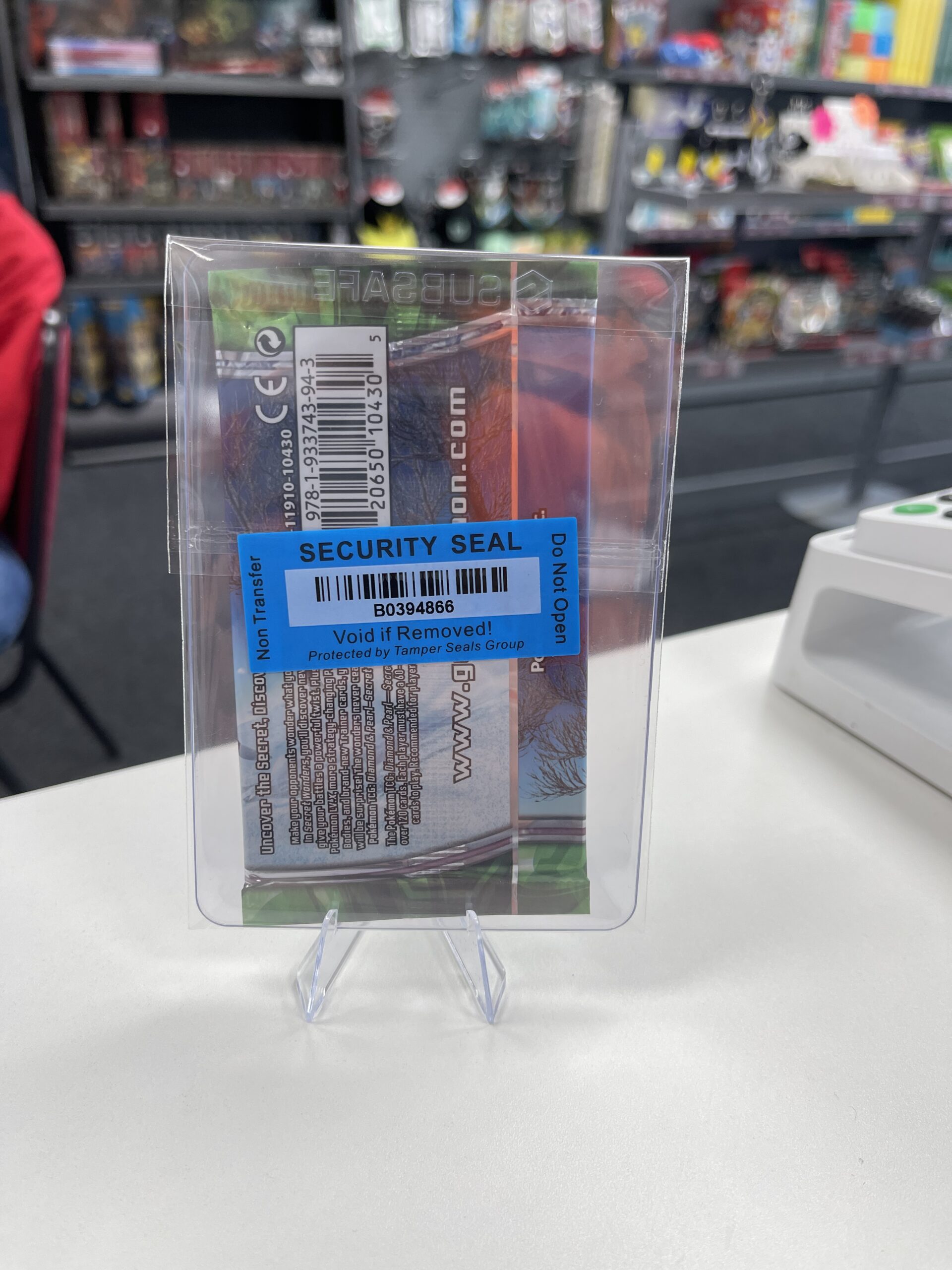 The back of a vintage Pokémon booster pack in a case, showing the WLC security seal and barcode for authenticity.
